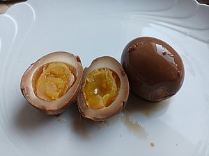 Zwei eingelegte Eierhälften und ein ganzes eingelegtes Ei auf einem Teller.